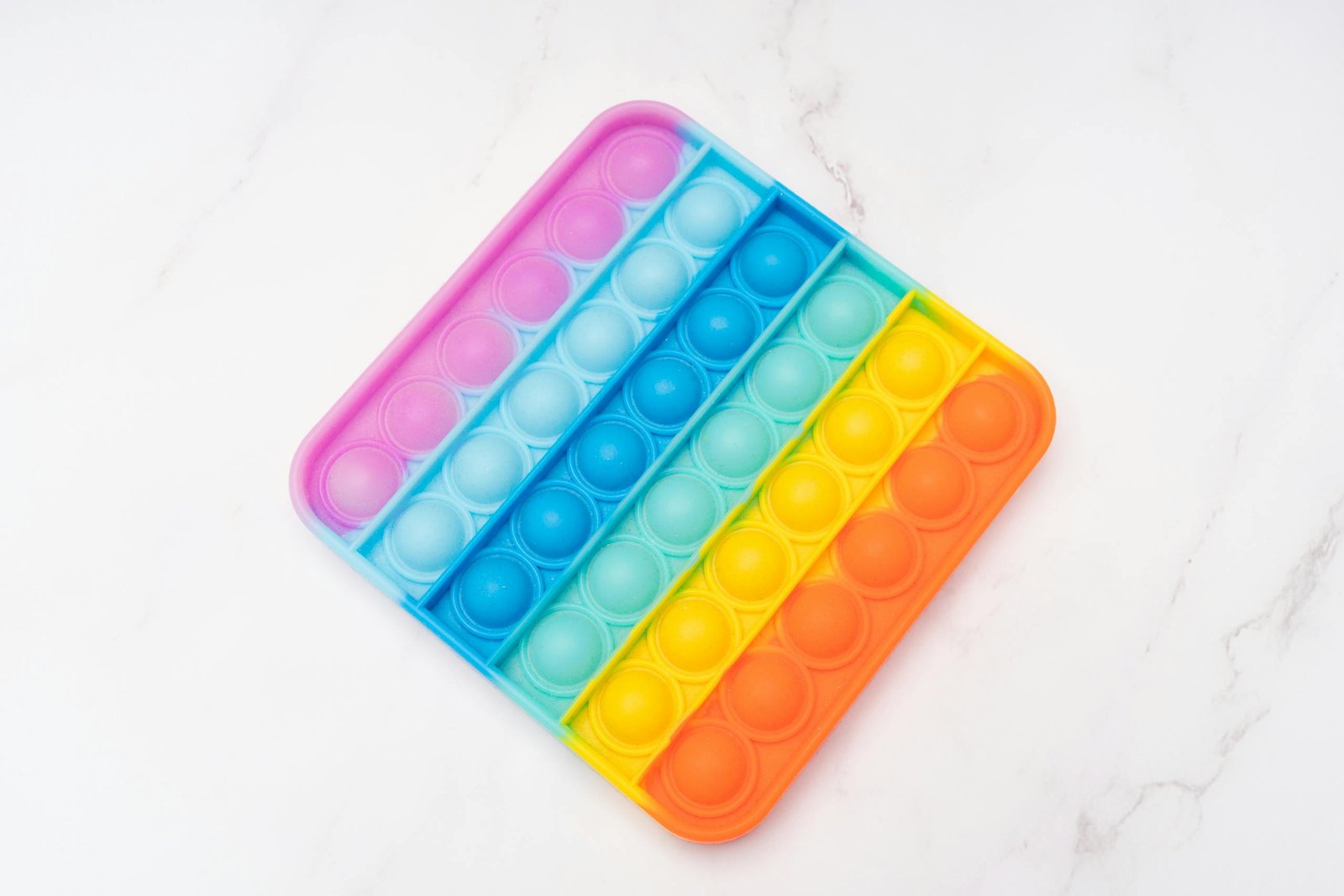 Rainbow Pop It fidget toy on a bright white surface, perfect for stress relief.