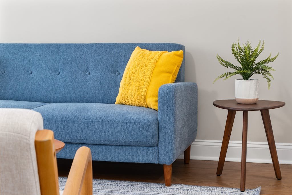 Contemporary living room featuring a stylish blue sofa with a bright yellow pillow and a wooden side table.