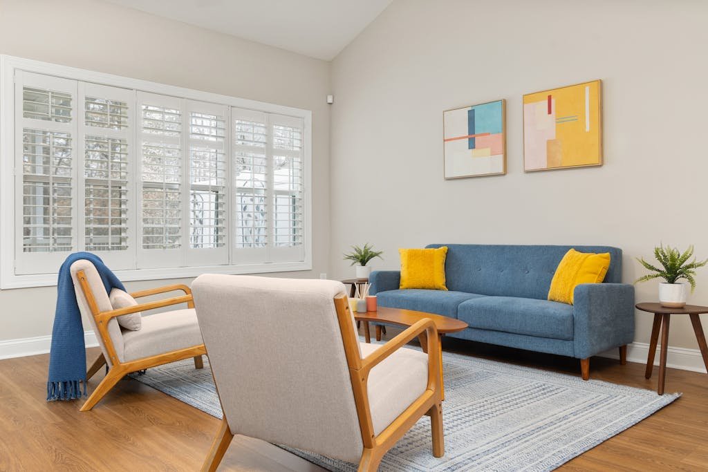 Stylishly designed living room featuring a blue sofa, abstract art, and natural light from large windows.